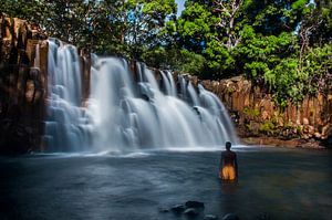 Cascade tropicale avec des nageurs locaux en maillot jaune