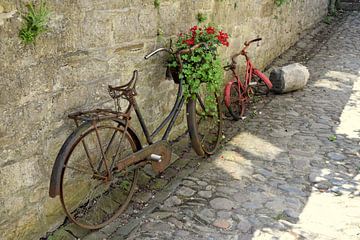 Roestige oude fietsen in een steegje in Durbuy, België van Nicolette Vermeulen