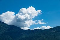 witte wolken boven beboste bergen en blauwe lucht