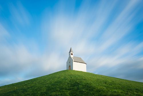 Kerk op een heuvel onder bewegende wolken