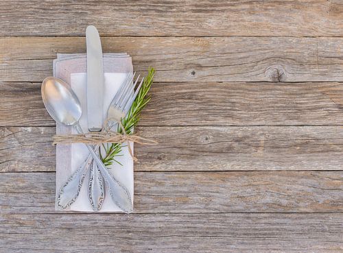 Rustiek diner menu tafel het plaatsen met servet, zilveren bestek en rozemarijn takje