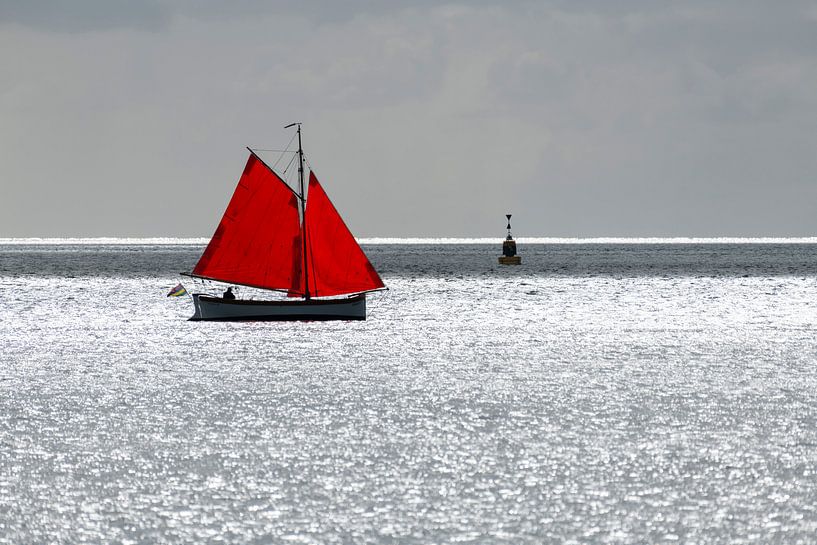 Zeilbootje met rood zeil tegen de schittering van de zon op de Waddenzee nabij het eiland Terschelli van Tonko Oosterink