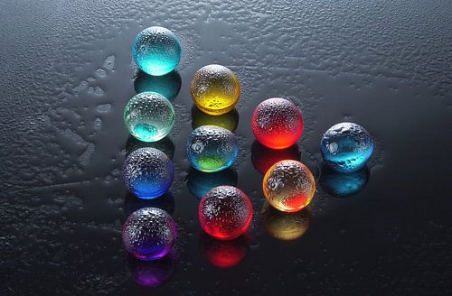 Gekleurde knikkers op een zwarte glasplaat.