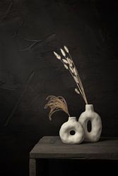 Donker stilleven met droogbloemen in witte kruiken