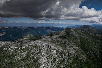 Landschaft unten (Luftaufnahme aus einem Gleitschirm) mit grünen Bergen, stark bewölkt. Montenegro