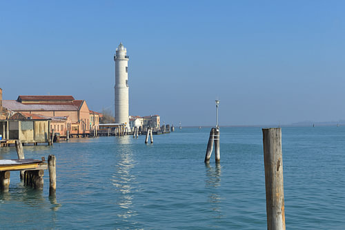 Le phare de Murano se dresse fièrement à côté des bâtiments de la lagune de Venise