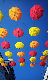 Fliegende, bunte Schirme vor blauem Himmel