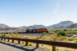 Güterzug auf dem Weg durch die raue Landschaft von Arizona. von Martijn Bravenboer
