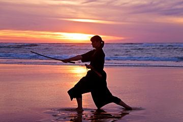 Junge Samurai Frau mit japanischen Schwert (Katana) bei Sonnenuntergang am StrandUntergang am Strand von Eye on You