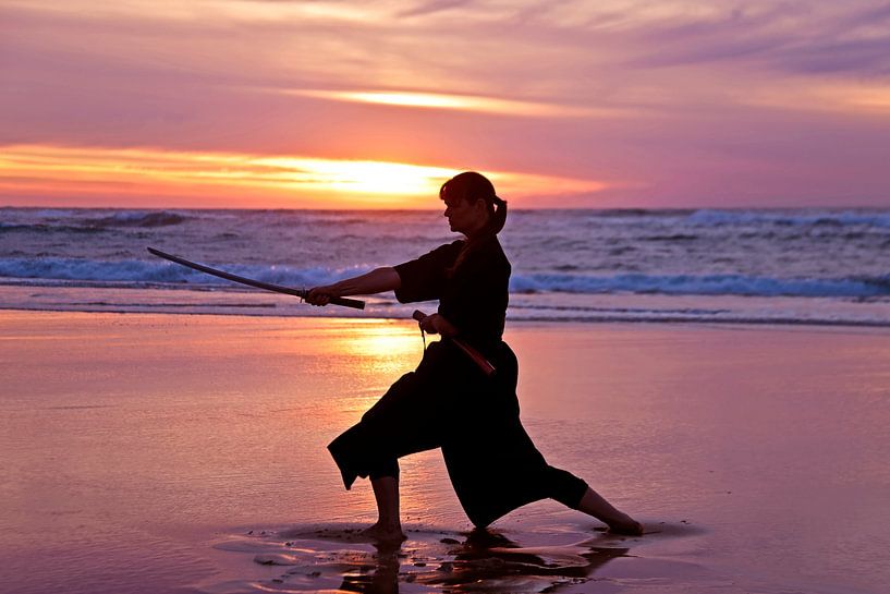 Junge Samurai Frau mit japanischen Schwert (Katana) bei Sonnenuntergang am StrandUntergang am Strand von Eye on You