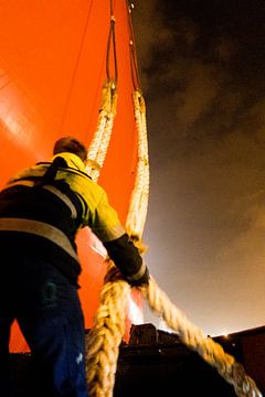 Havenwerker vangt trossen op om een schip aan te meren