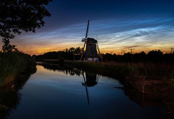 Lichtende nachtwolken boven een windmolen in de polder van Theo van Veenendaal