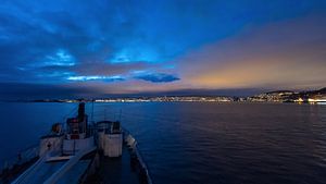 Approche du navire Hurtigruten MS Lofoten vers la ville illuminée de Trondheim, la nuit. sur Robert Ruidl