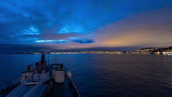 Anfahrt des Hurtigruten Schiffes MS Lofoten auf die beleuchtete Stadt Trondheim in der Nacht