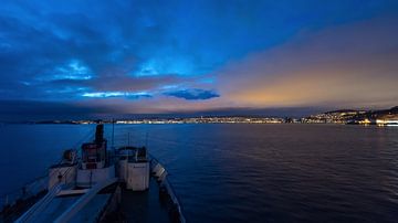 De nadering van het Hurtigruten-schip MS Lofoten tot de verlichte stad Trondheim bij nacht van Robert Ruidl