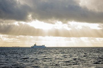 Zonnestralen boven de veerboot op Waddenzee van thomaswphotography