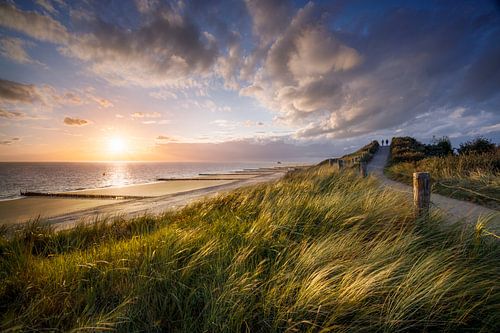 Sunset on the coast of Zeeland, dune path with two walkers