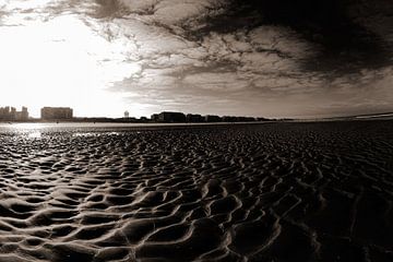 Vast Zandstrand Met Stedelijke Skyline Onder Heldere Blauwe Lucht in Sepia van Youri Mahieu