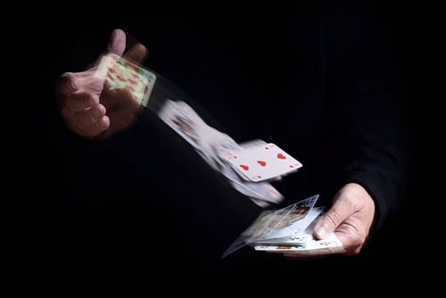 two hands shuffle falling cards with motion blur against a black background, business metaphor or co
