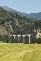 Rood treintje over brug in Zwitserland