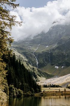 A mountain lake with forest, with rock and snow above it