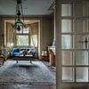 Huiskamer met blauwe sofa en piano in verlaten huis van Inge van den Brande