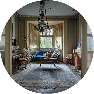 Huiskamer met blauwe sofa en piano in verlaten huis van Inge van den Brande