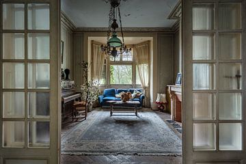 Huiskamer met blauwe sofa en piano in verlaten huis