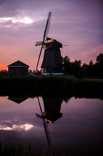 Sunset on a dike in west friesland with a windmill in the background