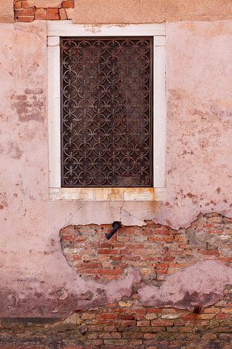 Roze vergane muur met een rechthoekig raam en gietijzerwerk in Venetië