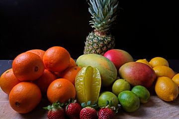 Sinaasappels, mango's, papaja's, aardbeien, ananas, limoenen en citroenen op een houten schijf