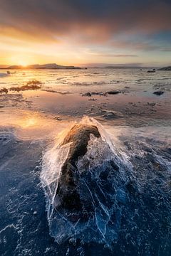 Gebroken ijs rond een steen tijdens een mooie zonsopkomst langs de kust van Zweden.