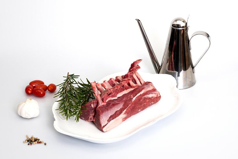 White dish with a rack of lamb and accompanying ingredients by Wim Stolwerk