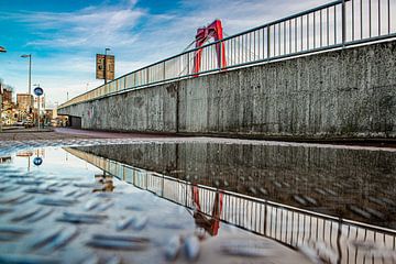 Reflectie van de Willemsbrug in een regenplas. van PicArt010