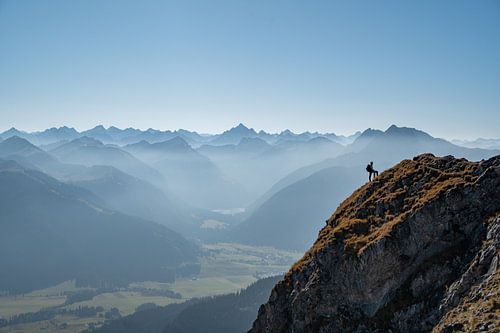 Klimmer op de top van de Aggenstein met uitzicht op het Tannheimer Tal en de Allgäuer Alpen, zoals de Hochvogel