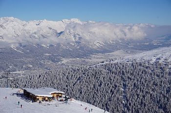Blick auf eine Skipiste, Hütte, verschneite Bäume, die Stadt Innsbruck und die Nordkette vom Skigebi