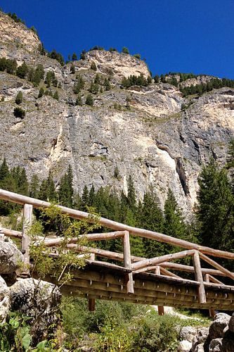 A wooden bridge at the foot of a steep rock face