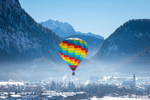 Heteluchtballonnen sieren de lucht boven een besneeuwd Inzell in Duitsland