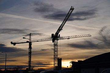 Vakwerkkranen op een grote bouwplaats bij zonsondergang in Duitsland
