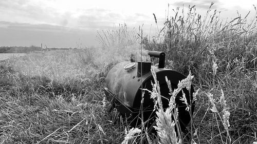 Still life of a quietly smoking barbecue among the tall grass in a meadow