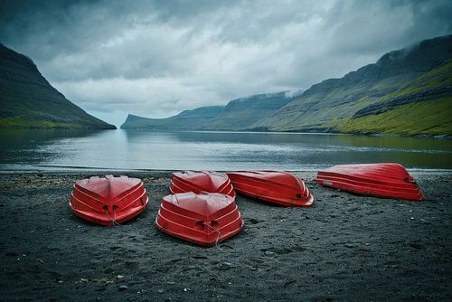 Rote Boote an einem einsamen schwarzen Strand auf den Färöer Inseln