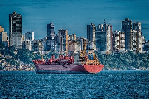 Frachtschiff verankert in der Bucht aller Heiligen mit den Skylinen der Stadt von Salvador, Brasilie