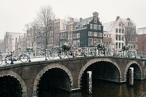 Brug en grachtenpanden in Amsterdam in de sneeuw