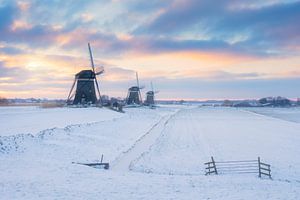 Drie molens bij zonsopkomst in een winter landschap