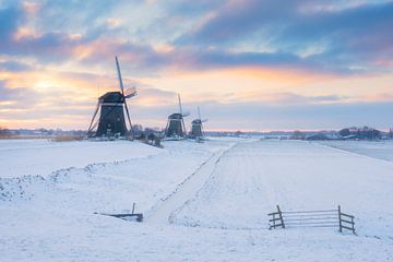 Drie molens bij zonsopkomst in een winter landschap