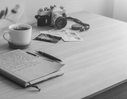 Gemütlicher Heimarbeitsplatz mit Notizbuch, Füllfederhalter, analoger Kamera und Kaffee – Digital Detox Lifestyle-Konzept von Animaflora PicsStock