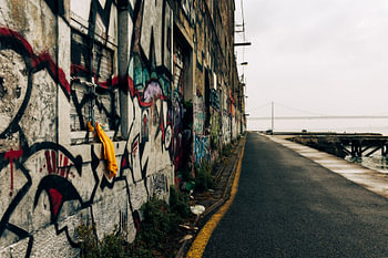 Verlaten straat met graffiti en brug in de verte - Lissabon
