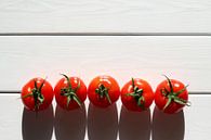 Vijf tomaten op een rij in de zon op een houten tafel van Maarten Pietersma thumbnail