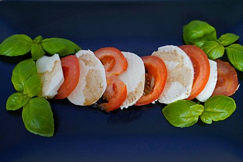 Tomaat, basilicum en mozarella met balsamico op een zwart dienblad