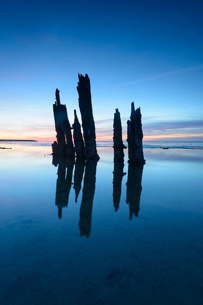 Einstellungssonne über Pfosten an den Gezeiten- sandflats am Ende des Tages von Sjoerd van der Wal Fotografie